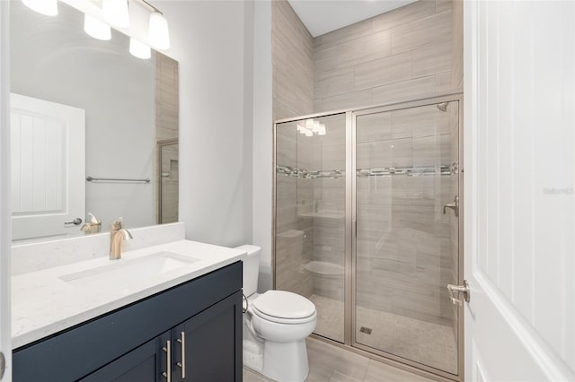 bathroom with a shower stall, toilet, and vanity
