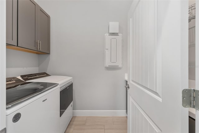 washroom with baseboards, washer and dryer, and cabinet space