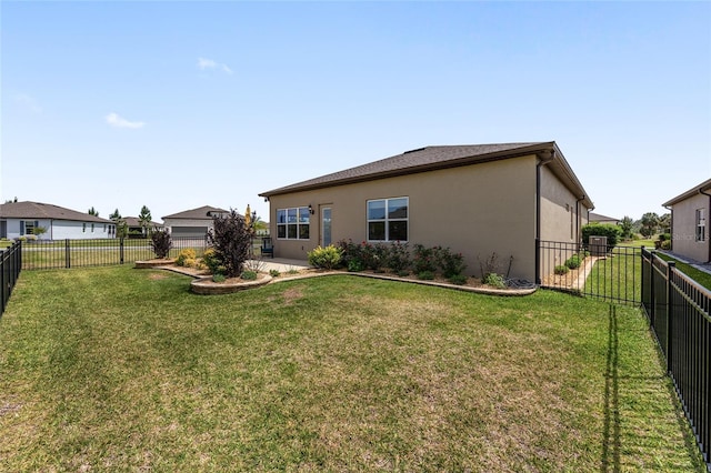 rear view of property featuring stucco siding, a fenced backyard, and a lawn