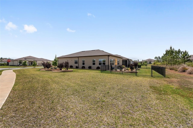back of property with stucco siding, fence, and a yard