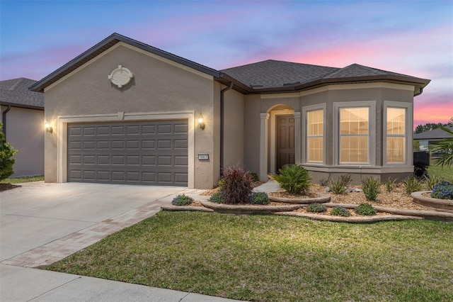 single story home with a garage, concrete driveway, a front yard, stucco siding, and roof with shingles