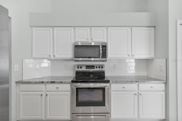 kitchen with white cabinets, decorative backsplash, light stone countertops, and appliances with stainless steel finishes