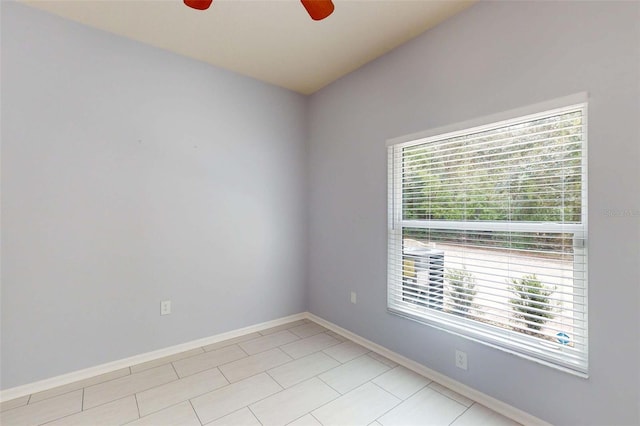 empty room featuring baseboards, a ceiling fan, and light tile patterned flooring