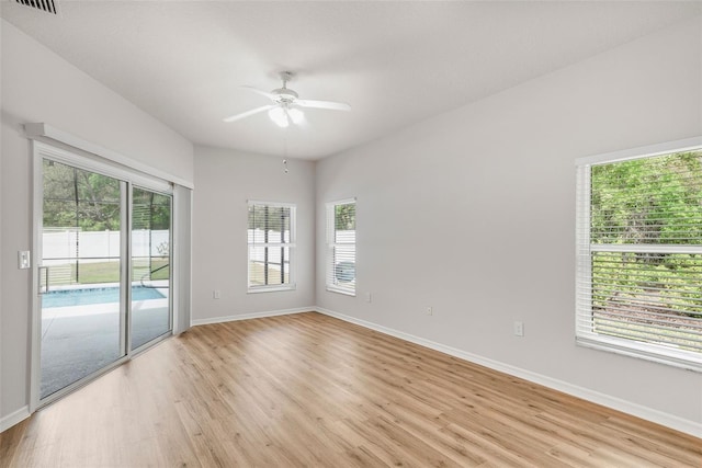 empty room featuring visible vents, light wood finished floors, baseboards, and a ceiling fan
