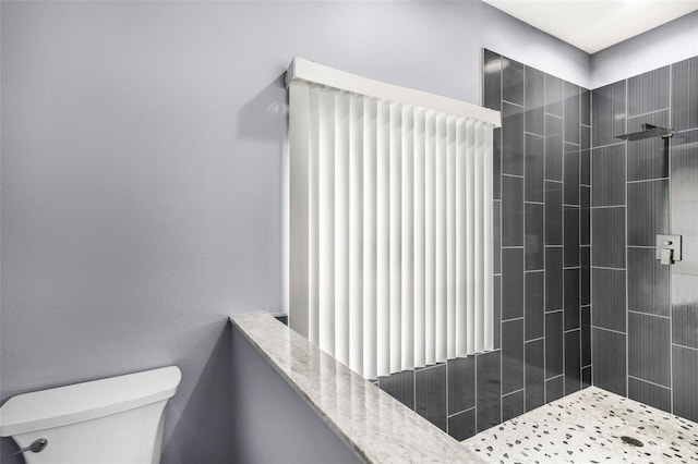 bathroom with radiator heating unit, toilet, and tiled shower