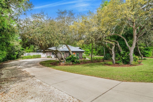 view of front of home with concrete driveway, fence, and a front yard