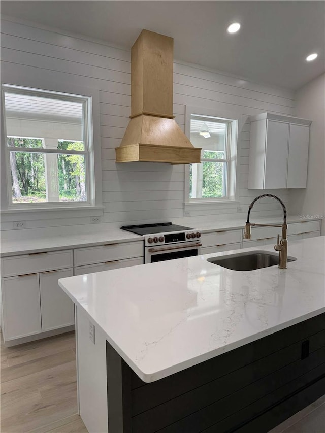 18890 SW 60th St, Dunnellon, FL 34432 - kitchen featuring light stone counters, a sink, premium range hood, electric range, and light wood finished floors
