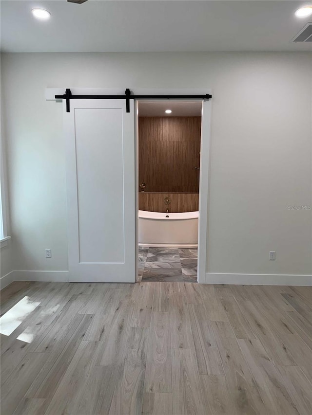 18890 SW 60th St, Dunnellon, FL 34432 - empty room with wood finished floors, a barn door, recessed lighting, and baseboards