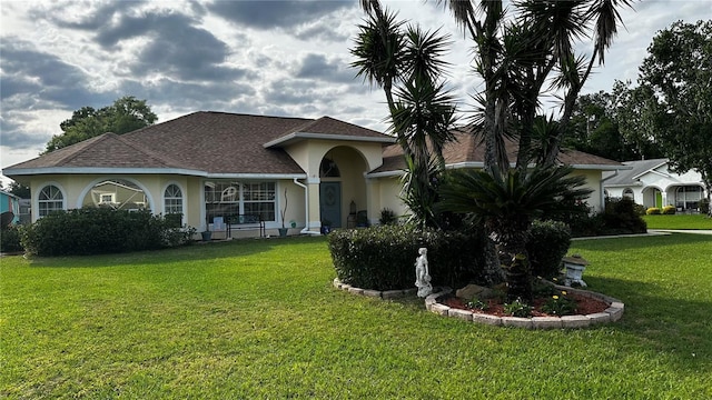 mediterranean / spanish-style home featuring a shingled roof, a front yard, and stucco siding