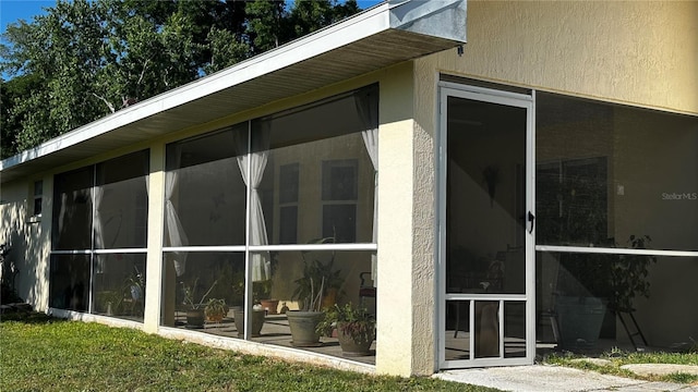 view of side of property with stucco siding and a sunroom