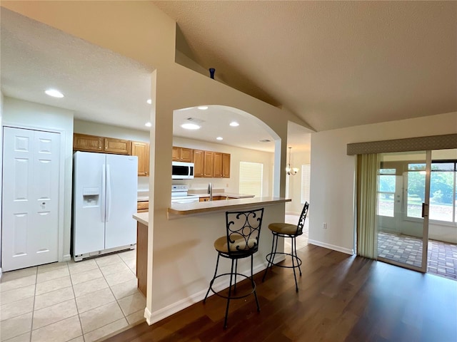 15782 SW 16th Avenue Rd, Ocala, FL 34473 - kitchen with brown cabinets, lofted ceiling, light wood finished floors, light countertops, and white appliances
