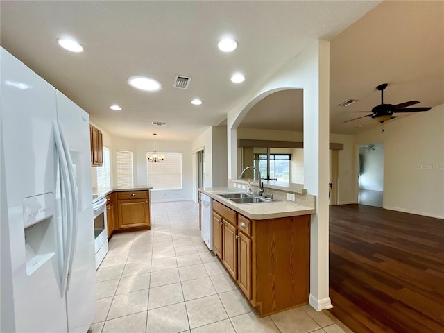 15782 SW 16th Avenue Rd, Ocala, FL 34473 - kitchen featuring a peninsula, a sink, visible vents, white appliances, and brown cabinetry