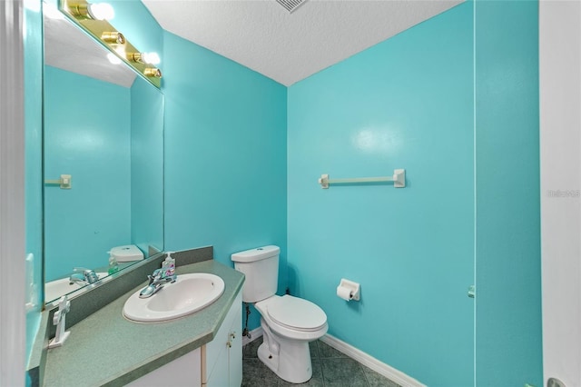 half bathroom with tile patterned flooring, toilet, vanity, baseboards, and a textured ceiling