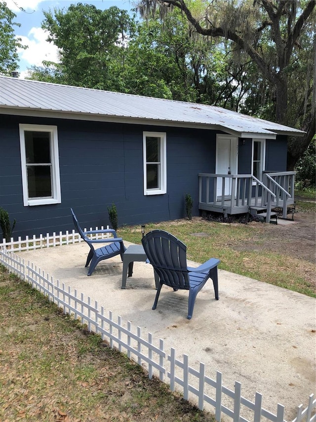 257 NE 8th St, Williston, FL 32696 - rear view of property featuring fence, metal roof, and a patio
