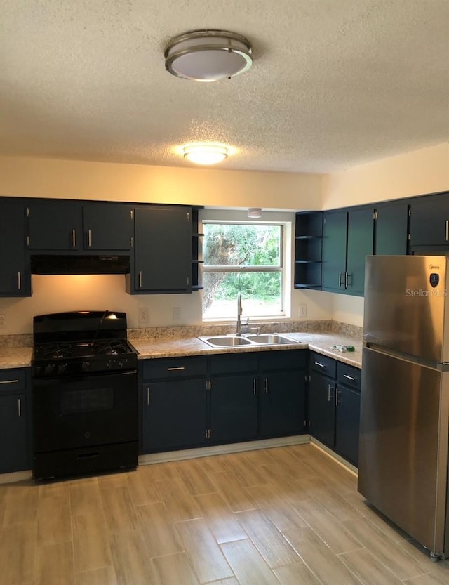 257 NE 8th St, Williston, FL 32696 - kitchen featuring open shelves, a sink, freestanding refrigerator, under cabinet range hood, and black range with gas stovetop