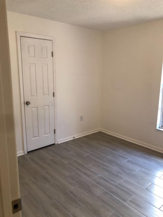 257 NE 8th St, Williston, FL 32696 - empty room featuring dark wood-type flooring, baseboards, and a textured ceiling