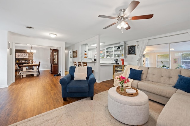219 NW 7th St, Williston, FL 32696 - living area featuring baseboards, visible vents, wood finished floors, and ceiling fan with notable chandelier