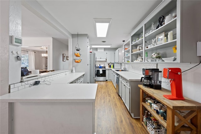 219 NW 7th St, Williston, FL 32696 - kitchen featuring open shelves, appliances with stainless steel finishes, light wood finished floors, light countertops, and decorative backsplash