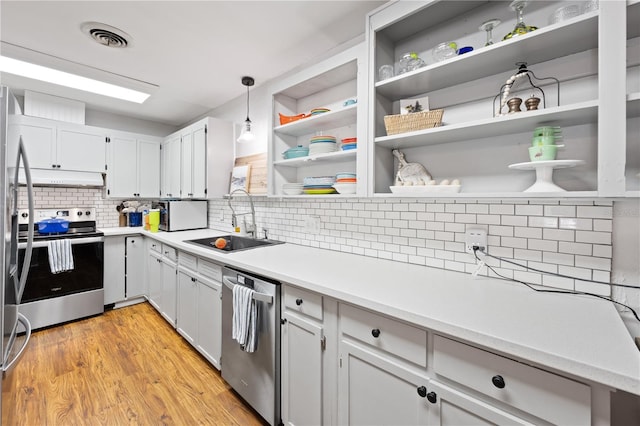 219 NW 7th St, Williston, FL 32696 - kitchen with appliances with stainless steel finishes, a sink, decorative backsplash, under cabinet range hood, and visible vents
