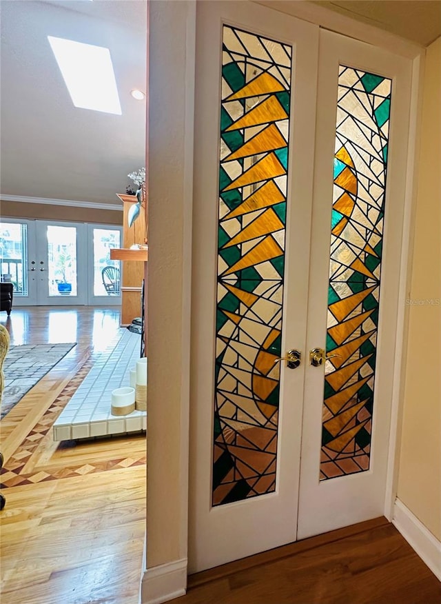 interior details featuring baseboards, ornamental molding, french doors, and wood finished floors