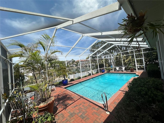 pool with a lanai, a patio, and a water view