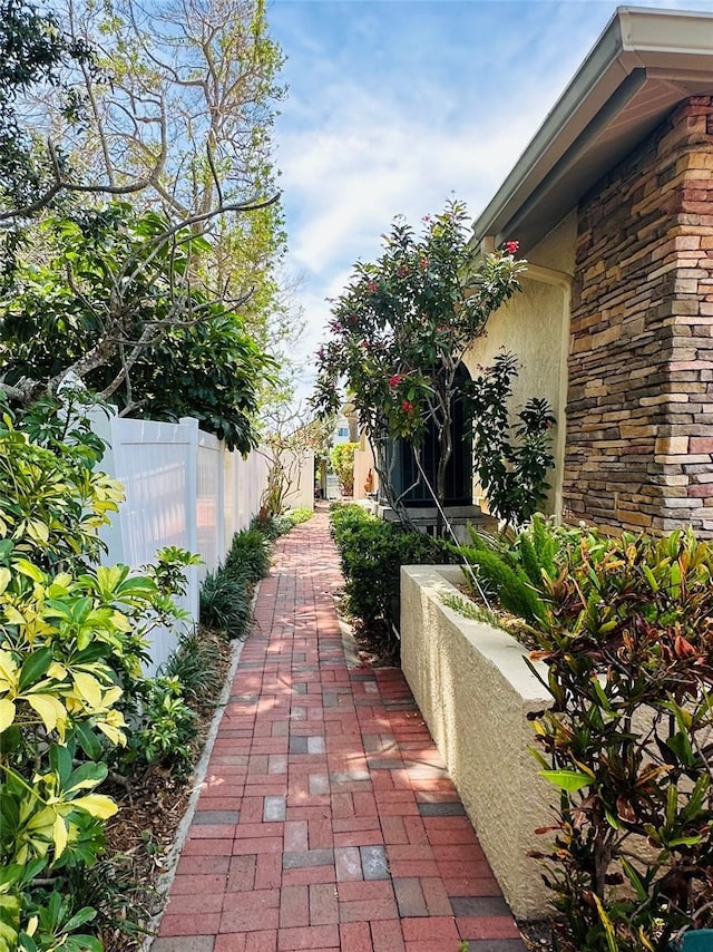 view of property exterior with fence, stucco siding, and stone siding