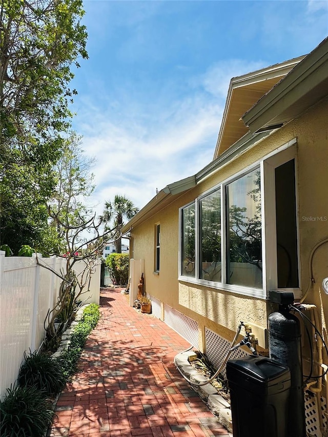 view of side of home featuring fence, a patio, and stucco siding