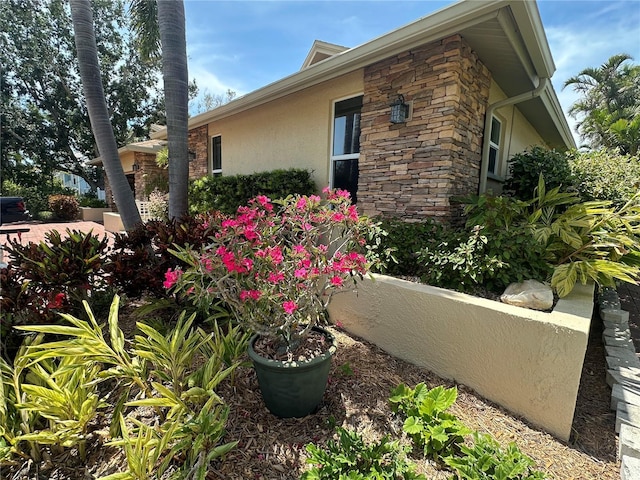 view of side of property featuring stucco siding and stone siding