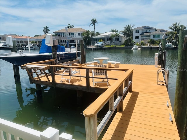 view of dock featuring a water view, boat lift, and a residential view