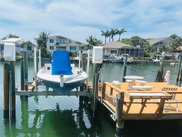 dock area with a residential view, boat lift, and a water view