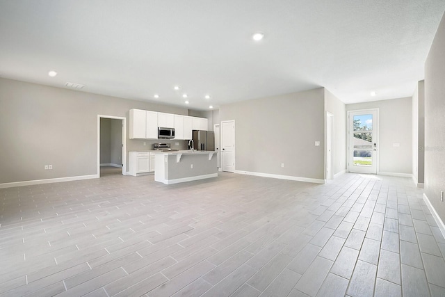 unfurnished living room featuring visible vents, baseboards, recessed lighting, and light wood-style floors