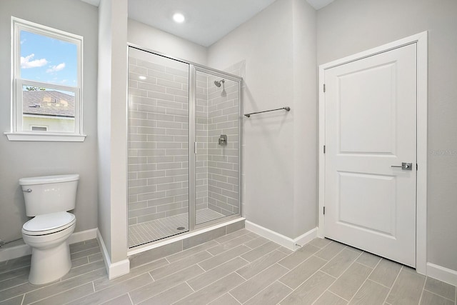 full bath featuring a shower stall, wood finish floors, toilet, and baseboards