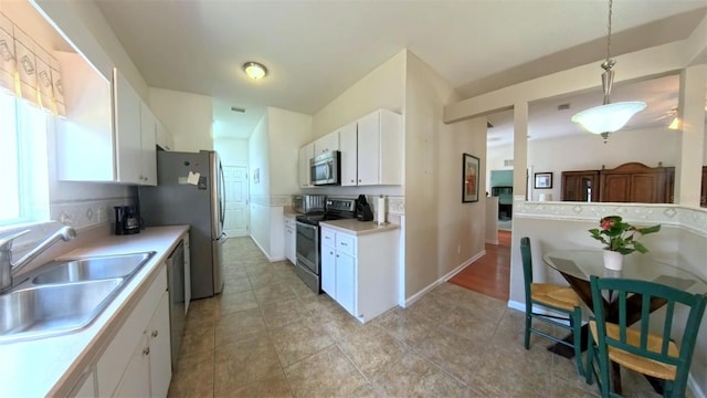2323 NW 55th Avenue Rd, Ocala, FL 34482 - kitchen featuring stainless steel appliances, a sink, white cabinets, light countertops, and hanging light fixtures