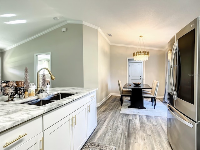 kitchen featuring light wood-style flooring, light stone counters, white cabinets, refrigerator with glass door, and a sink