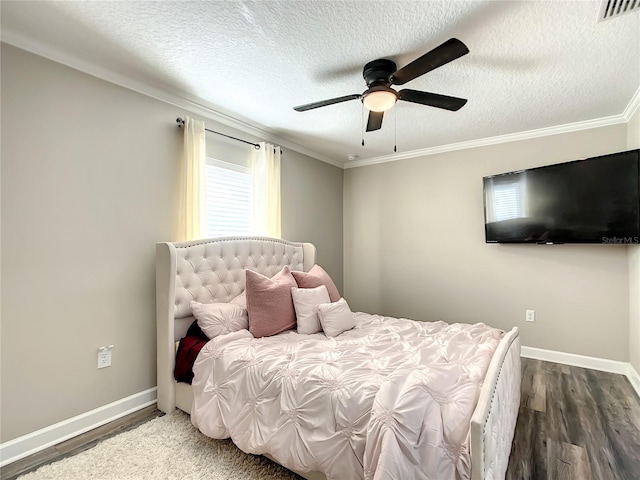 bedroom featuring crown molding, wood finished floors, a textured ceiling, baseboards, and visible vents