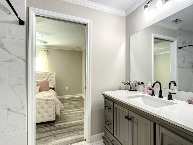 bathroom featuring a textured ceiling, visible vents, crown molding, and vanity