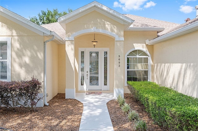 property entrance featuring a shingled roof and stucco siding