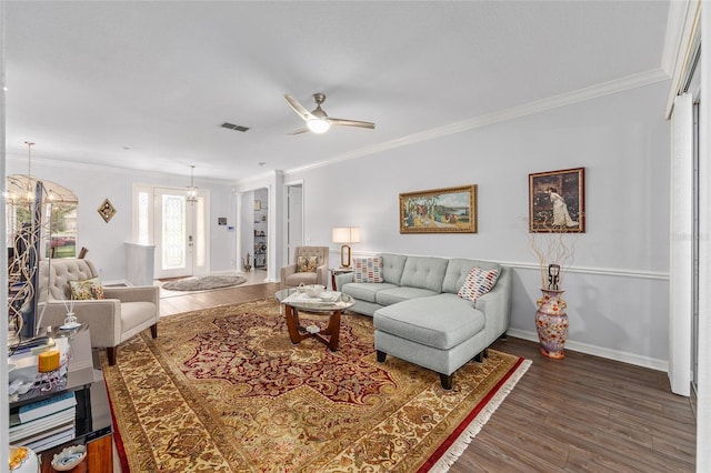 living area featuring wood finished floors, visible vents, ceiling fan, and crown molding