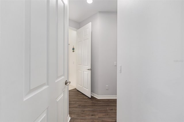 hall with baseboards and dark wood-type flooring