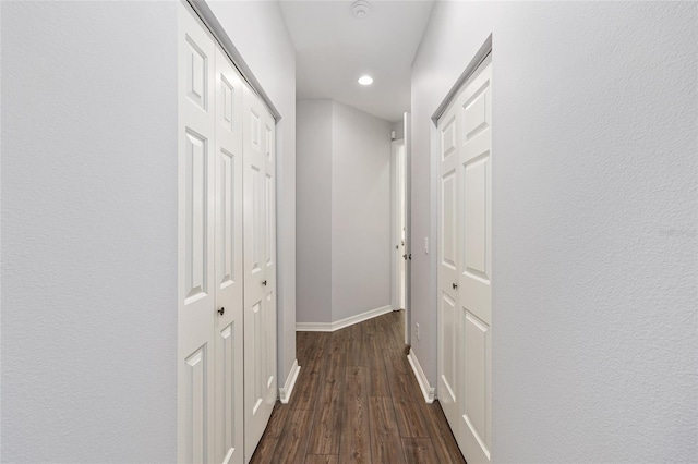 hallway featuring baseboards, recessed lighting, and dark wood finished floors