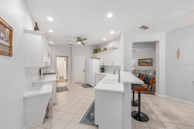 kitchen featuring a kitchen breakfast bar, a sink, white appliances, and light tile patterned floors