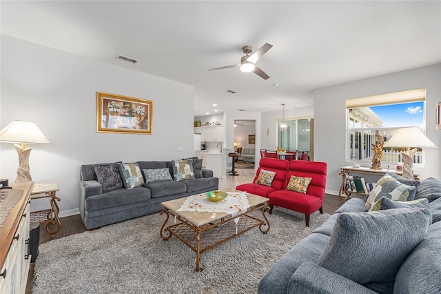 living area featuring light wood-style flooring, visible vents, a ceiling fan, and baseboards