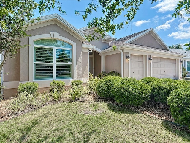 view of front of house featuring a garage, stucco siding, and a front lawn