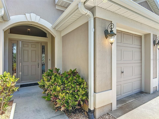 doorway to property with a garage and stucco siding