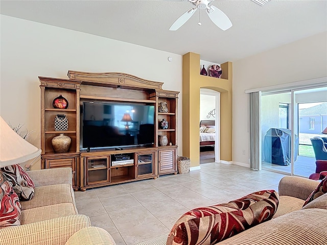 living room featuring a ceiling fan, arched walkways, and light tile patterned floors