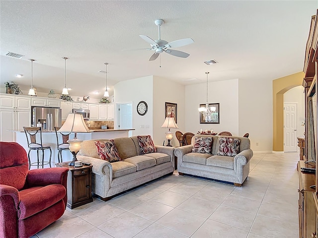 living room featuring visible vents, arched walkways, ceiling fan with notable chandelier, and light tile patterned floors