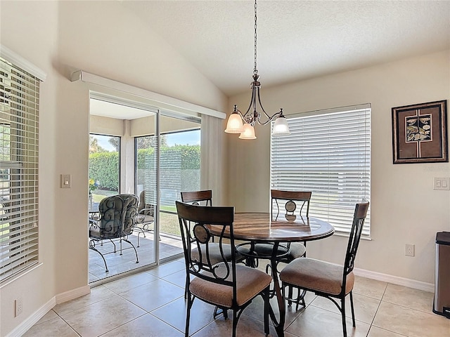 dining room featuring a notable chandelier, a textured ceiling, baseboards, light tile patterned floors, and lofted ceiling