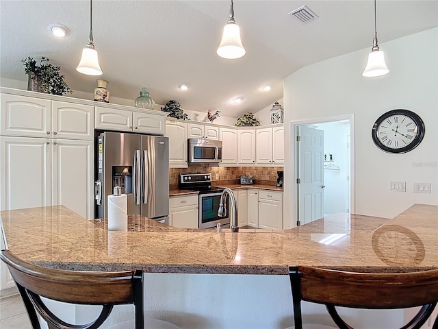 kitchen featuring visible vents, tasteful backsplash, a breakfast bar, stainless steel appliances, and white cabinetry