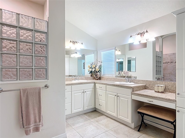 full bath featuring double vanity, vaulted ceiling, a sink, and tile patterned flooring