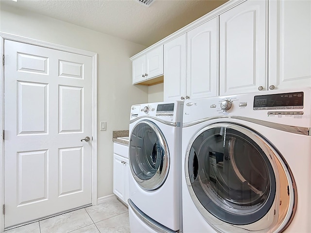 laundry room with a textured ceiling, cabinet space, light tile patterned floors, and washer and dryer